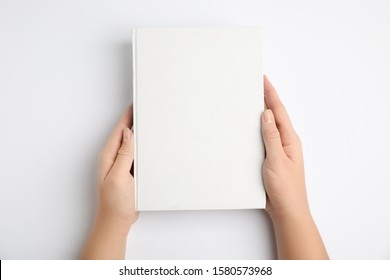 Woman holding book with blank cover on white background, top view