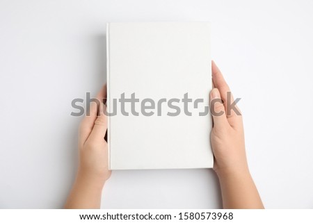 Woman holding book with blank cover on white background, top view