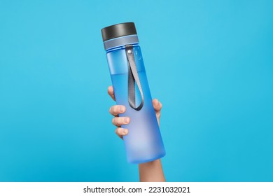 Woman holding bottle of drink on light blue background, closeup - Powered by Shutterstock