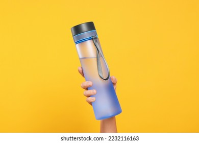 Woman holding bottle of drink on orange background, closeup