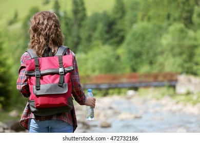 Woman holding bottle with fresh water on beautiful river landscape