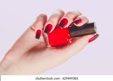 Woman holding bottle nail polish  Nail Polish  Art Manicure  Modern style red black Nail Polish  Stylish Colorful stiletto Nails isolated pink background  Beautiful female hand and beauty manicure