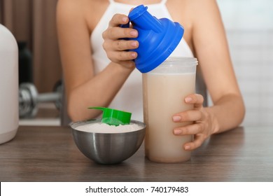 Woman Holding Bottle With Protein Shake At Table