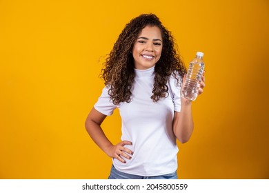 Woman holding a bottle of water on yellow background. Drink water!