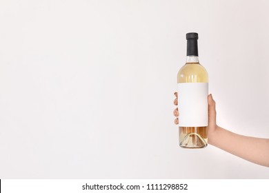 Woman Holding Bottle Of Wine On Light Background