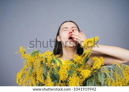 woman holding a bouquet of yellow flowers and sneezing