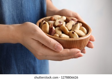 Woman Holding Bowl With Brazil Nuts On Grey Background, Closeup