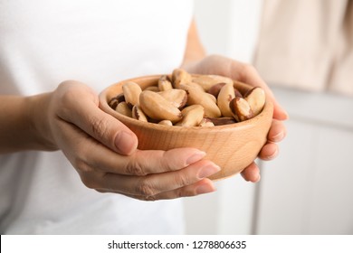 Woman Holding Bowl With Brazil Nuts On Blurred Background, Closeup