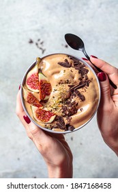 Woman Holding Bowl Of Chocolate Smoothie With Figs And Hemp Seeds, Gray Background. Healthy Vegan Food Concept.