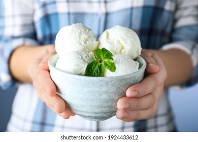 Woman holding bowl full of ice cream with mint, closeup