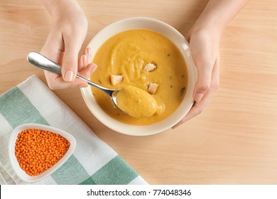 Woman Holding Bowl Of Homemade Lentils Creme Soup On Table