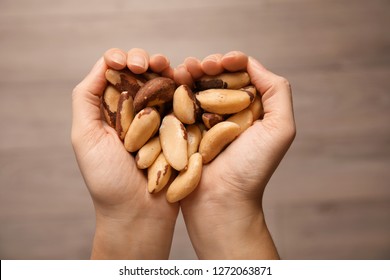 Woman Holding Brazil Nuts In Hands On Blurred Background, Top View