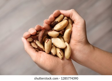 Woman Holding Brazil Nuts In Hands On Blurred Background, Top View