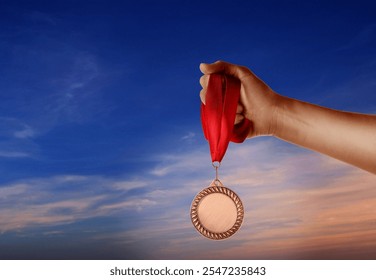 Woman holding bronze medal in hand against sky, closeup - Powered by Shutterstock