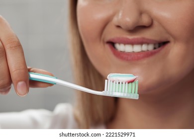 Woman Holding Brush With Toothpaste In Bathroom, Closeup