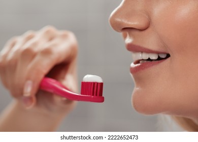 Woman Holding Brush With Toothpaste In Bathroom, Closeup