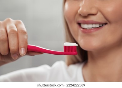 Woman Holding Brush With Toothpaste In Bathroom, Closeup