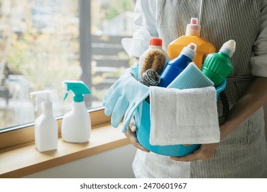 Woman holding a bucket of cleaning tools. A housewife cleaning. - Powered by Shutterstock