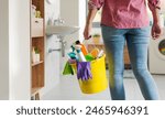 Woman holding a bucket with detergents and cleaning equipment, she is doing household chores