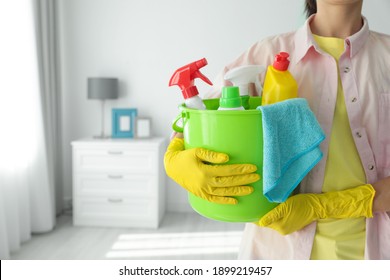 Woman Holding Bucket With Different Cleaning Supplies At Home, Closeup. Space For Text