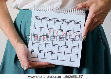 Woman holding calender with marked missed period. Unwanted pregnancy, woman's health and delay in menstruation. Period late