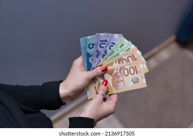 Woman is holding Canadian dollars in her hands. Canadian money in different nominals