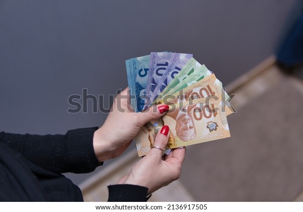 Woman is holding Canadian dollars in\
her hands. Canadian money in different\
nominals