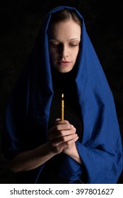 Woman Holding Candle And Praying. Dark Background