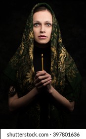 Woman Holding Candle And Praying. Dark Background