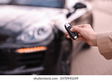 Woman holding car flip key near her vehicle outdoors, closeup
