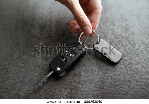 Woman\
holding car flip key on grey background,\
closeup