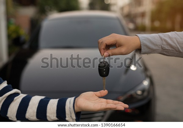 The woman is holding the car key after agreeing to\
buy and sell the car.