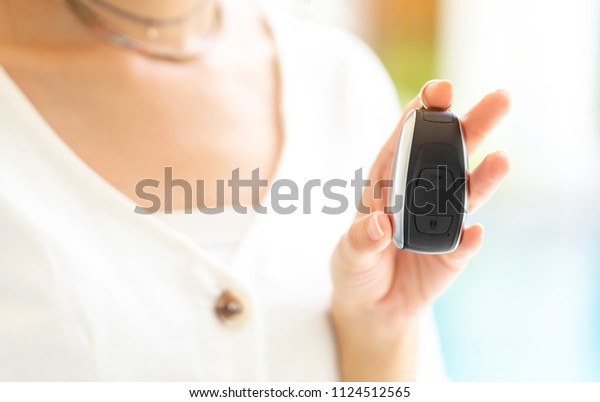 Woman holding Car key remote control in hands\
after buying new car from dealer, modern key style which can\
touching close while standing beside vehicle. Salesman giving\
remote control for rental