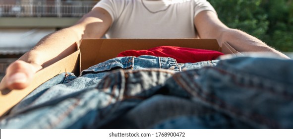 Woman holding card box with clothes inside. Donation Concept. Selective focus