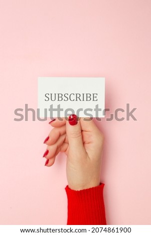 Woman holding card with SUBSCRIBE text, red and pink color combo
