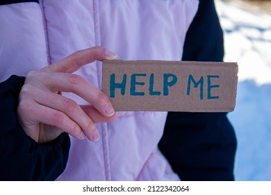 Woman holding cardboard with help me text.