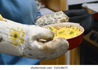 Woman Holding Casserole Dish Of Mexican Cheese Dip With Oven Mitts