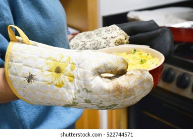 Woman Holding Casserole Dish Of Mexican Cheese Dip With Oven Mitts