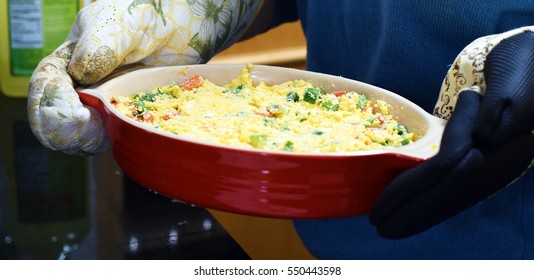 Woman Holding Casserole Dish Of Mexican Cheese Dip With Oven Mitts