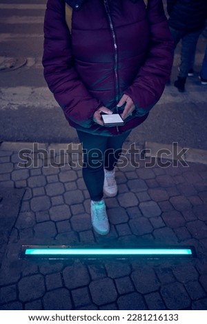 Woman holding cellphone and crossing the street.
