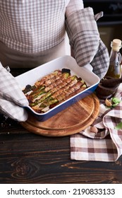 Woman Holding Ceramic Baking Dish With Baked Aspargus Covered With Bacon