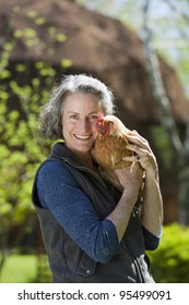 Woman Holding Chicken Outside Her Geodesic Home