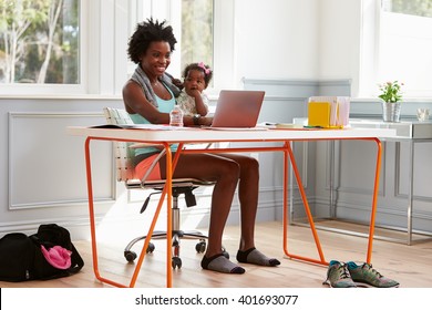 Woman Holding Child Using Computer At Home After Exercising