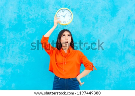 Woman Holding Clock Checking Time on Blue Background. Girl with timer counting down seconds for deadline
