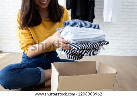 Woman holding Clothes with Donate Box In her room, Donation Concept.