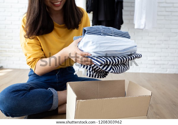自分の部屋に寄付箱を持つ服を持つ女性 寄付のコンセプト の写真素材 今すぐ編集