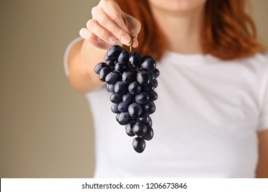 Woman holding cluster of fresh ripe juicy grapes, closeup