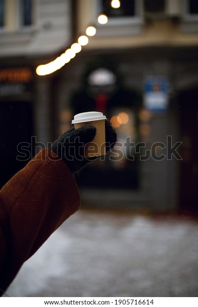 woman holding\
coffee in winter warm\
gloves\
