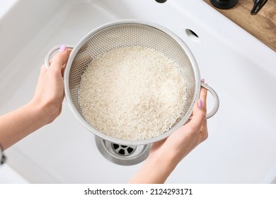 Woman Holding Colander With Raw Rice Over Sink, Closeup