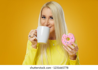 Woman holding colorful donut with sprinkles on a yellow background. Cup of coffee. Concept of food and Tasty - Powered by Shutterstock